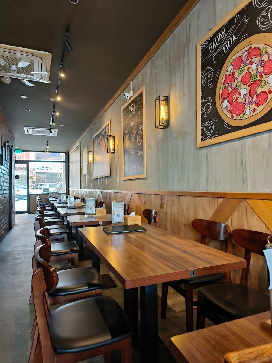 Inside Da Napoli Cafe: rows of wooden tables along a wood-panelled wall hung with pizza chalkboard art